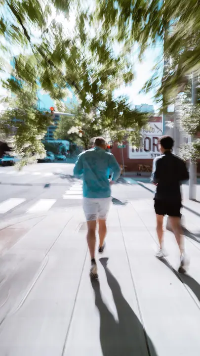 Two people walking a sunny city street