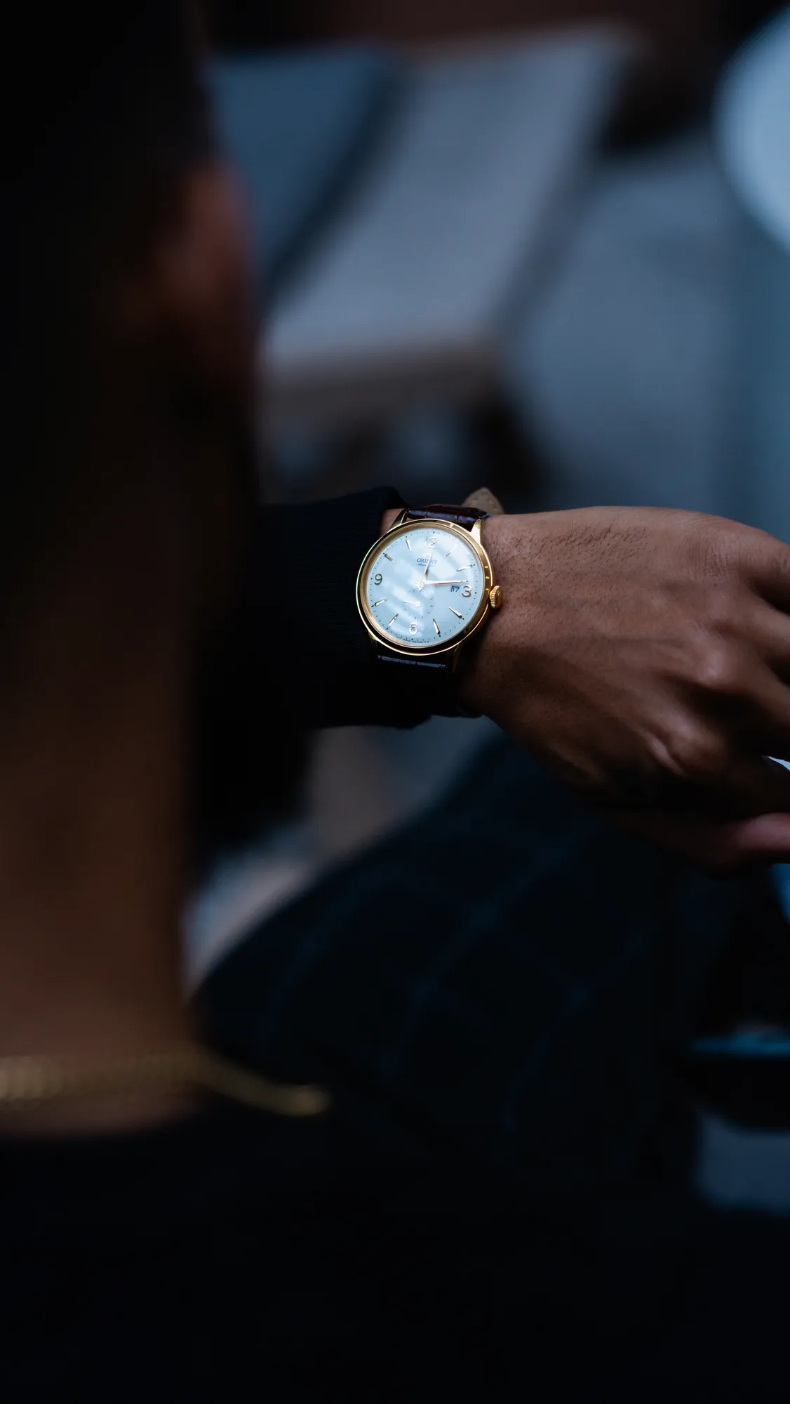 Gold watch on a wrist in low light