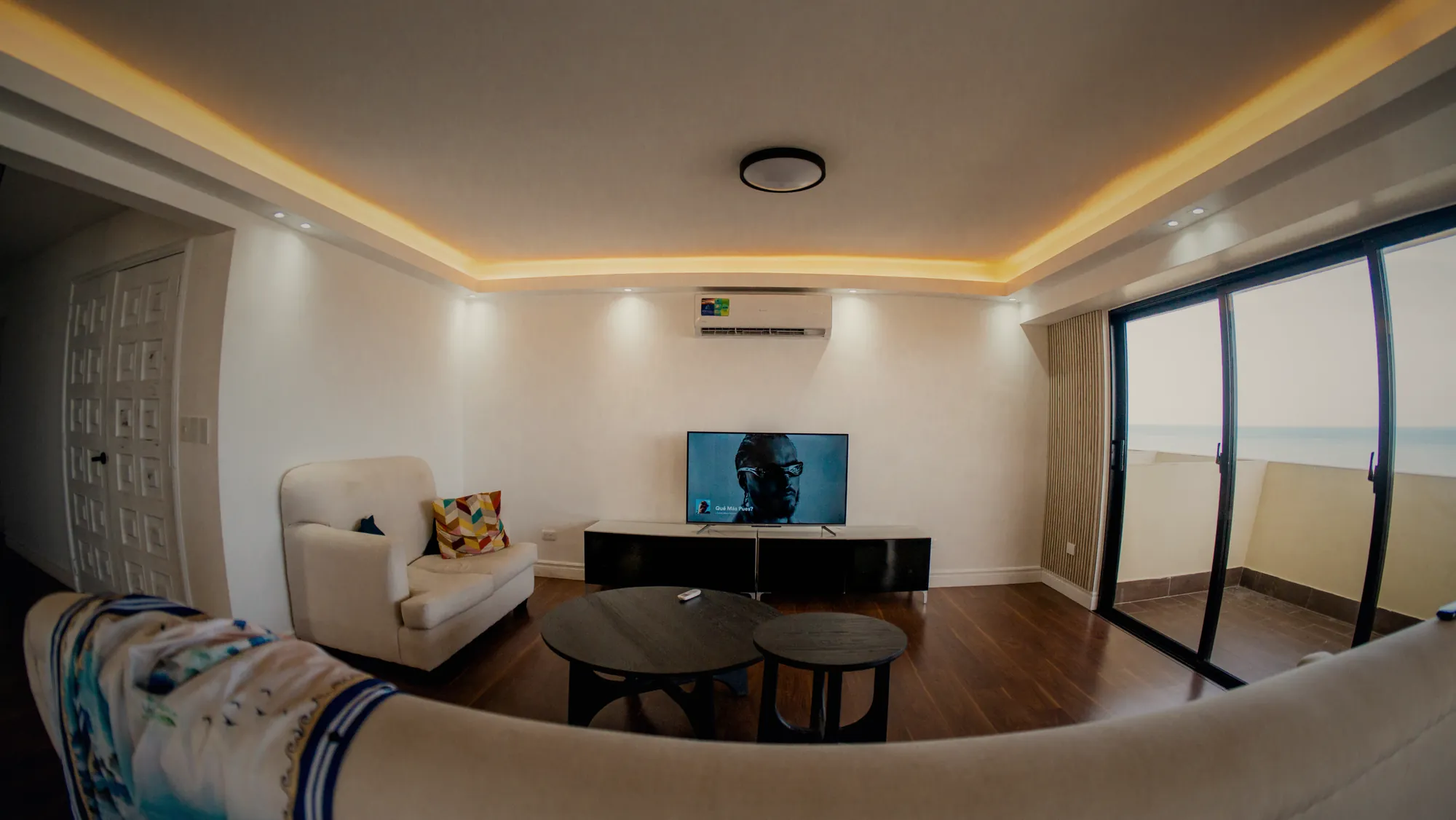 Wide-angle living room of a rental with a sea-view balcony